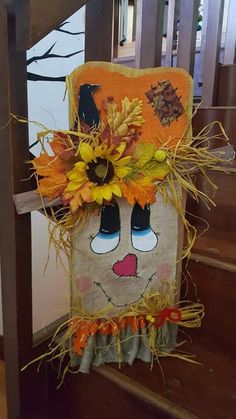 a scarecrow decoration with sunflowers and leaves on the head is sitting on some stairs