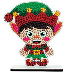 a beaded doll is sitting on top of a white stand and it looks like he's wearing a green hat