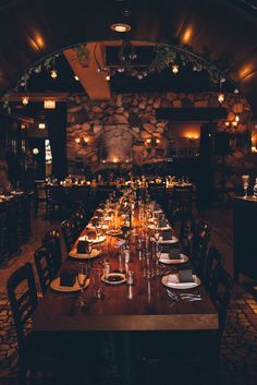 a long table with place settings is set up in the middle of a dimly lit room