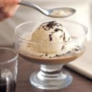 a person scooping ice cream into a glass bowl