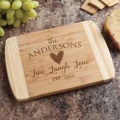 the personalized cutting board is next to some grapes and crackers