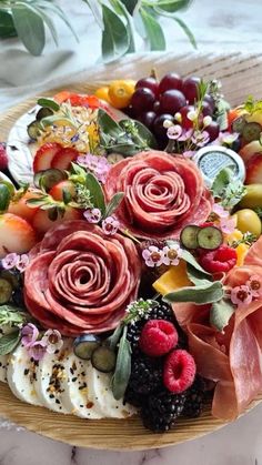 a platter filled with fruit and flowers on top of a table