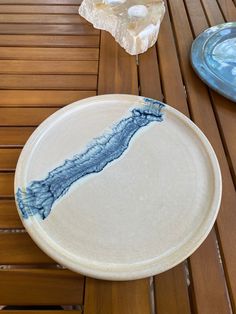 a white plate sitting on top of a wooden table next to a blue glass bowl