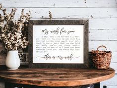 a wooden sign sitting on top of a table next to a vase with flowers in it