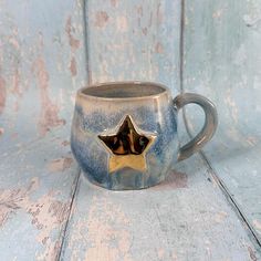 a ceramic mug with a gold star on the inside sits on a blue wooden surface