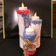 two crocheted candles are sitting next to each other on a black countertop