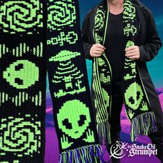 a woman standing next to a black and green scarf with skulls on it, in front of a purple background