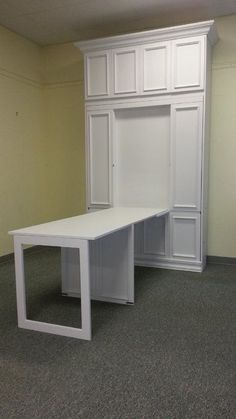 an empty room with a white desk and cupboards on the wall, next to a carpeted floor