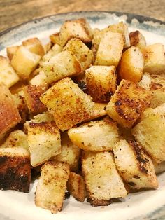 a white plate topped with fried potatoes on top of a wooden table