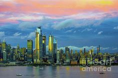 the city skyline is lit up at sunset with clouds in the sky and boats on the water