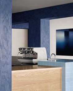 a coffee machine sitting on top of a counter next to a blue tiled kitchen wall