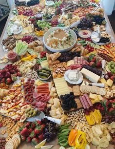 a table covered with lots of different types of cheeses, crackers and fruit