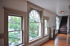 an empty room with wooden floors and three windows