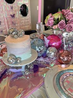 a table topped with a white cake covered in frosting and lots of pink flowers