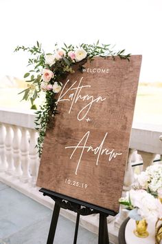 a wooden sign with flowers and greenery on it