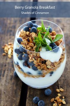 a glass filled with yogurt, granola and blueberries