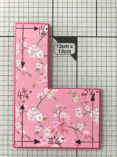 two pieces of pink fabric with white flowers on them, one has a ruler in front of it