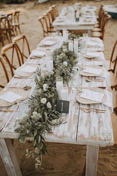 a long table set with place settings and flowers on it for an outdoor dinner party