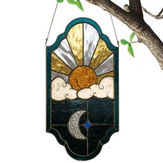 a stained glass sun and moon hanging from a tree