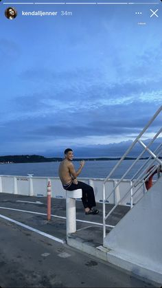 a man sitting on top of a white railing next to the ocean