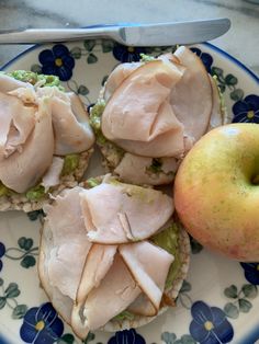 four sandwiches on a plate with an apple