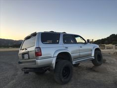 a silver suv parked on top of a dirt field