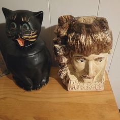 two ceramic cats sitting on top of a wooden table