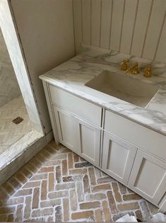 a bathroom with white cabinets and marble counter tops