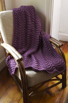 a chair with a purple knitted blanket on it's back in front of a door