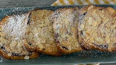 several pieces of bread with powdered sugar on top sitting on a blue platter