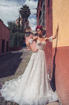 a woman in a wedding dress leaning against a wall with her hand on the side