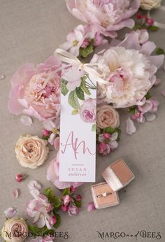 some pink flowers and two small boxes with the name ann on them sitting next to each other