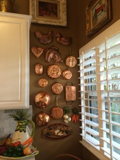 there are many plates on the wall above the sink and in front of the window