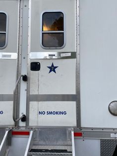 the side of a white trailer with blue stars on it's door and windows