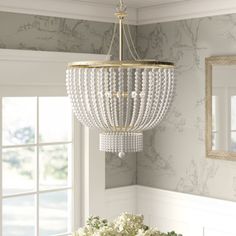 a chandelier hanging from the ceiling in a dining room with white flowers and greenery