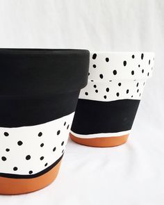 two black and white pots with polka dots on them sitting next to each other in front of a white background