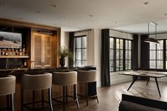 a living room filled with furniture and lots of windows next to a wooden bar table