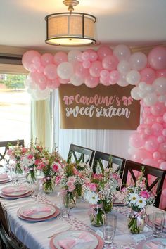 a table set up with pink and white balloons