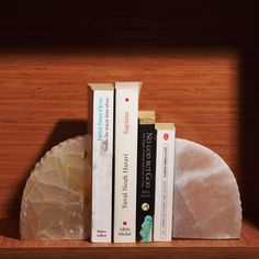 two books are sitting on a book shelf with some kind of rock next to them