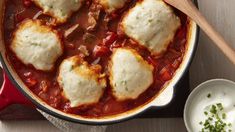 some ravioli and tomato sauce in a red skillet next to a bowl of sour cream