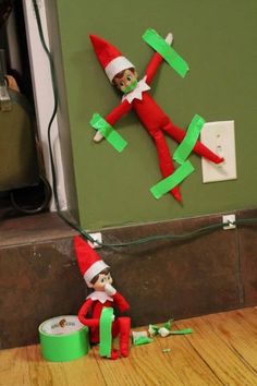 an elf is sitting on the floor next to a green box and some paper airplanes