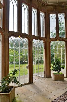 the inside of a building with large windows and potted plants in front of them