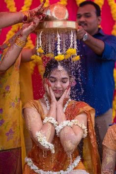 a woman is covered in water while getting her head sprayed with orange and yellow flowers