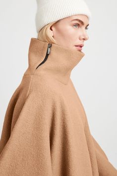 A stylish wool winter cloak, our Avery Cape is the ideal choice for heading out into the cold. Fashioned from Italian virgin wool and offered in fresh neutrals that pair well with any combination of clothing, this women’s wool cape is designed with a loose silhouette. Simple. Elegant. Cozy. Layer her over anything for an instant ready-to-go look. Avery's high collar has a side zipper for style and easy wear. This wool winter cape is lined for added warmth and comfort. | Maritza Fall Merino Wool Outerwear, Modern Merino Wool Outerwear For Fall, Fall Merino Wool Outerwear With Funnel Neck, Beige Cape For Winter Workwear, Oversized Merino Wool Outerwear For Winter, Chic Cashmere Cape For Winter, Fall Merino Wool Outerwear For Cold Weather, Wool Outerwear With Funnel Neck For Fall, Fall Cashmere Outerwear With Funnel Neck