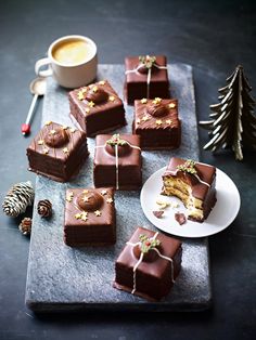 there are many pieces of chocolate cake on the tray next to a cup of coffee