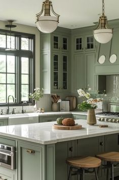 a kitchen with green cabinets and white counter tops, two stools in front of the island