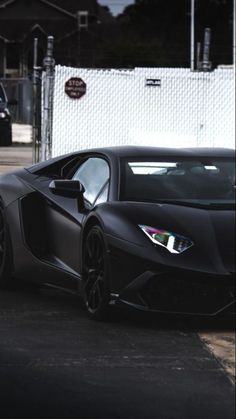 a black sports car parked in front of a white fence