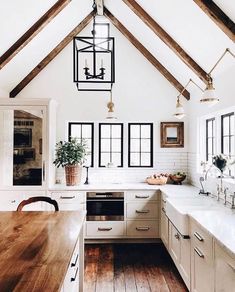 a kitchen with white walls and wooden beams on the ceiling is decorated with potted plants