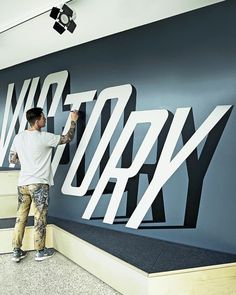 a man is painting the letters on a wall