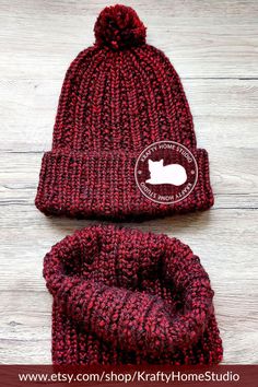 a red knitted hat and booties sitting on top of a wooden floor